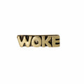 Gold pin with 'WOKE' text on a white background